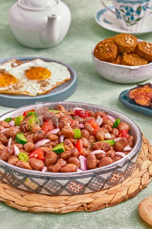 Close-up of a dish of foul medames with vegetables, falafel tablets, a plate of fried egg, Arabic breakfast, oriental breakfast, arab restaurant