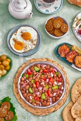 Close-up of a dish of foul medames with vegetables, falafel tablets, dish of fried egg,  Arabic breakfast, oriental breakfast, arab restaurant