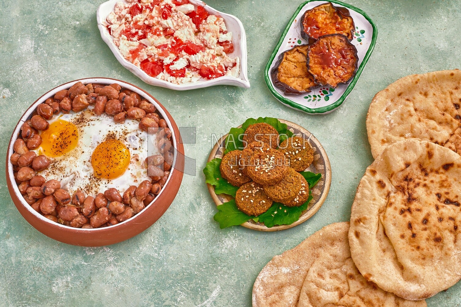Dish of foul medames with fried egg, falafel tablets, fried eggplant, cheese with tomato, Arabic breakfast, oriental breakfast, arab restaurant