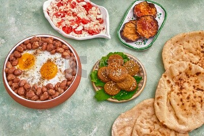 Dish of foul medames with fried egg, falafel tablets, fried eggplant, cheese with tomato, Arabic breakfast, oriental breakfast, arab restaurant