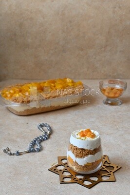 Cup of kunafa with mango and cream beside a tray of kunafa with mango and cream, Ramadan sweets