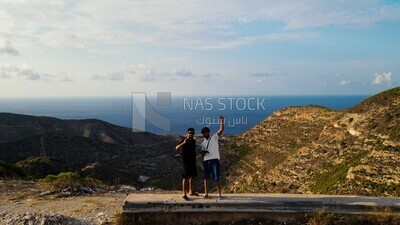 drone footage of two men standing beside a green mountain taking a selfie in libya
