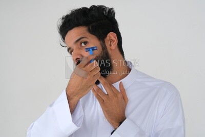 Saudi man holding a razor blade, removing facial hair