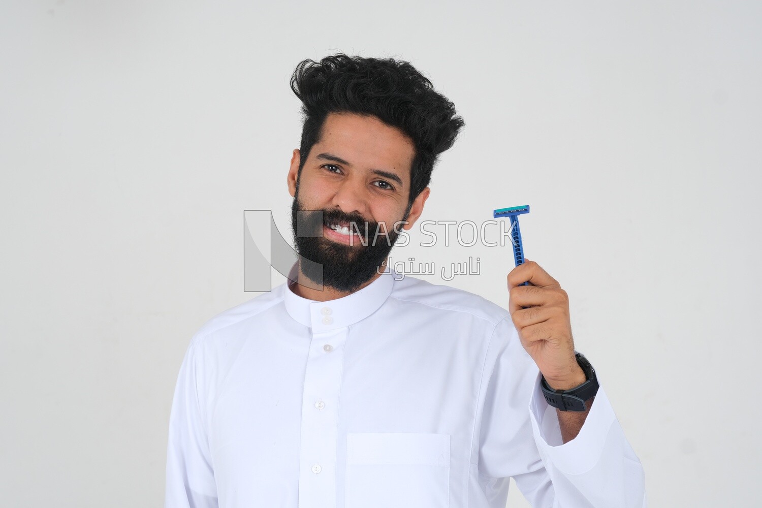 Saudi man holding a razor blade, removing facial hair, skin care and hygiene, shaving his beard, self-care, Saudi model, white background