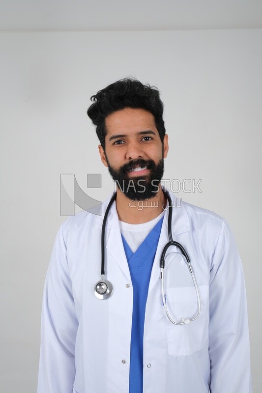 رجل سعودي يرتدي معطفًا طبيًا وسماعة طبيب ، الخلفية البيضاء ، الطب والرعاية الصحية