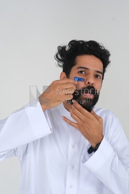 Saudi man holding a razor blade, removing facial hair, skin care and hygiene, shaving his beard, self-care, Saudi model, white background
