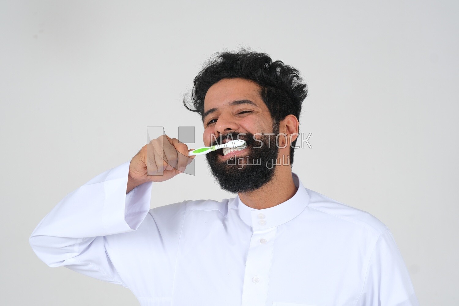 Saudi man holding a toothbrush, brushing his teeth with toothpaste, skincare and hygiene, self-care, Saudi model, white background