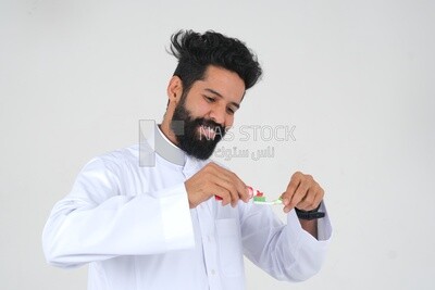 Saudi man holding a toothbrush, brushing his teeth with toothpaste, skincare and hygiene, self-care, Saudi model, white background