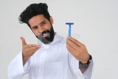 Saudi man holding a razor blade, removing facial hair, skin care and hygiene, shaving his beard, self-care, Saudi model, white background