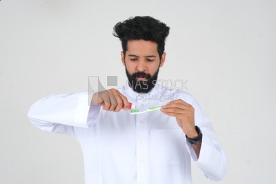 Saudi man holding a toothbrush, brushing his teeth with toothpaste, skincare and hygiene, self-care, Saudi model, white background