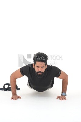 رجل سعودي يقوم بتمارين الإحماء ، والضغط ، وكمال الأجسام ، ونمط الحياة الصحي ، وبناء العضلات ، وخلفية بيضاء ، موديل سعودى