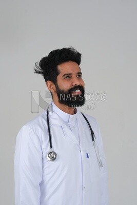 رجل سعودي يرتدي معطفًا طبيًا وسماعة طبيب ، الخلفية البيضاء ، الطب والرعاية الصحية