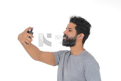 Saudi man holding a perfume bottle, applying perfume, selfcare, skin care and hygiene, Saudi model, white background