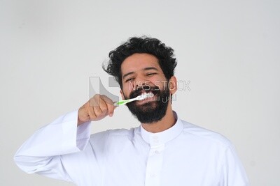 رجل سعودي يحمل فرشاة الأسنان ، ينظف أسنانه بمعجون الأسنان ، العناية بالبشرة والنظافة ، الرعاية الذاتية ، موديل سعودى ، الخلفية البيضاء
