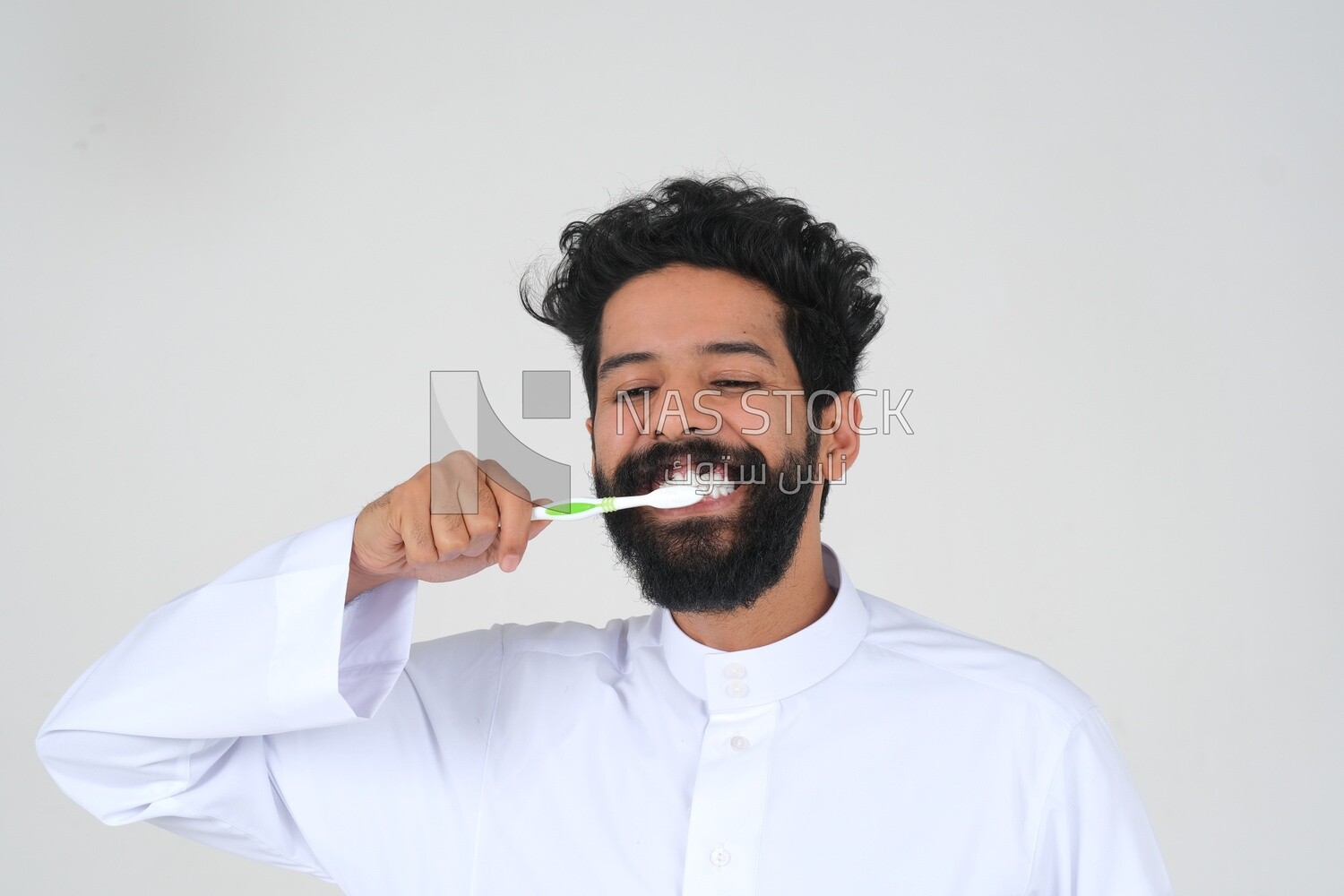 Saudi man holding a toothbrush, brushing his teeth with toothpaste, skincare and hygiene, self-care, Saudi model, white background