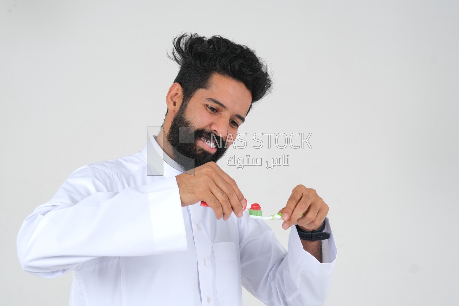 Saudi man holding a toothbrush, brushing his teeth with toothpaste, skincare and hygiene, self-care, Saudi model, white background