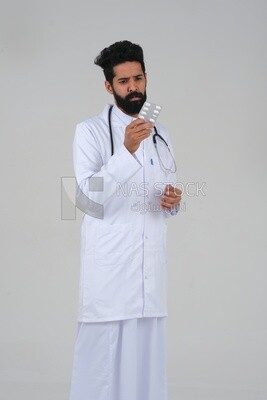 Saudi man wearing a medical coat and a stethoscope, holding a medicine tape, white background, medicine and health care, Saudi model