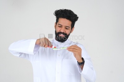 Saudi man holding a toothbrush, brushing his teeth with toothpaste, skincare and hygiene, self-care, Saudi model, white background