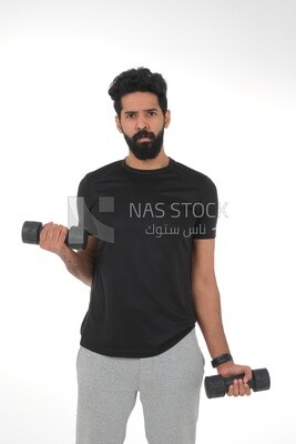 رجل سعودي يرتدي ملابس رياضية ، يمارس الدمبل ، كمال الأجسام ، نمط حياة صحي ، بناء العضلات