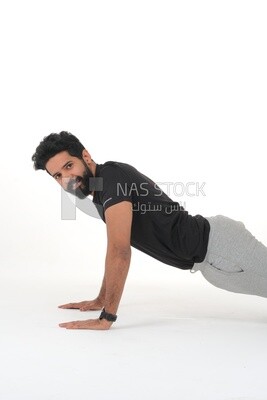 رجل سعودي يقوم بتمارين الإحماء ، والضغط ، وكمال الأجسام ، ونمط الحياة الصحي ، وبناء العضلات ، وخلفية بيضاء ، موديل سعودى
