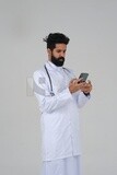 Saudi man wearing a medical coat and a stethoscope, using his mobile, white background, medicine and health care, Saudi model