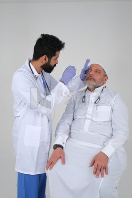 Saudi man wearing a medical coat and a stethoscope, checking the patient&#39;s eyes, white background, medicine and health care, Saudi model