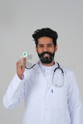 رجل سعودي يرتدي معطفًا طبيًا وسماعة طبيب ، الخلفية البيضاء ، الطب والرعاية الصحية