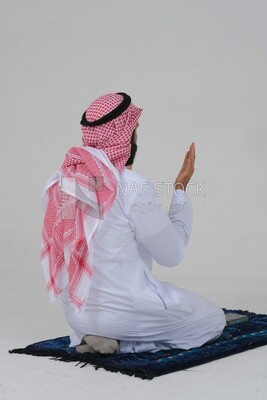 ظهر رجل سعودي يرتدي ثوبا أبيض يجلس على سجادة الصلاة ، يدعو الله ، يصلي على سجادة الصلاة ، الإسلام والعبادة ، خلفية بيضاء ، موديل سعودي.