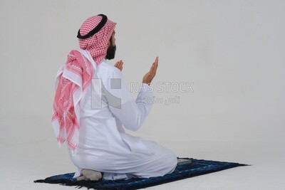 back of a Saudi man wearing a white dress sitting on the prayer rug, praying to god, praying on the prayer rug, Islam and worship, white background, Saudi model