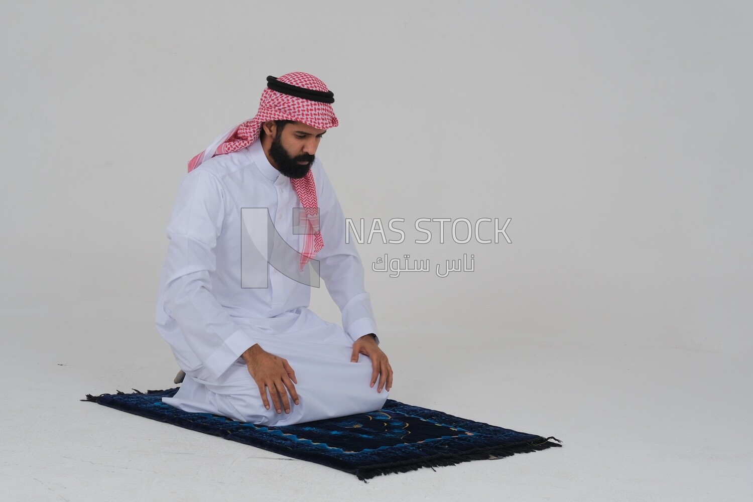 Saudi man wearing a white dress sitting on a chair, reading Quran, Islam and worship, Saudi model, white background