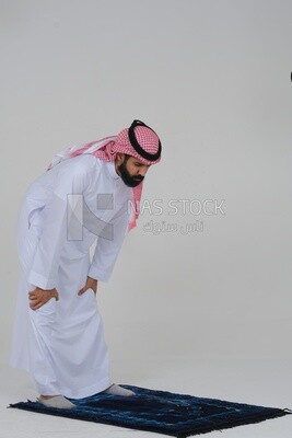 Saudi man wearing a white thobe and shemagh praying on the prayer rug, praying to god, Islam and worship, white background, Saudi model