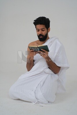 رجل سعودي يرتدي لباس الاحرام ويحمل كتاب القران الكريم ،  الدعاء لله ، الاسلام والعبادة ، يؤدي الحج والعمرة ، اذكار وادعية ، خلفية بيضاء ، موديل سعودي.