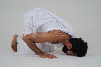 Saudi man wearing the Ihram dress, praying on the prayer rug