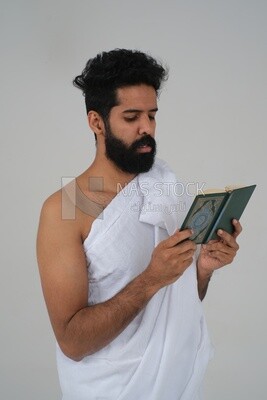 رجل سعودي يرتدي لباس الاحرام ويحمل كتاب القران الكريم ،  الدعاء لله ، الاسلام والعبادة ، يؤدي الحج والعمرة ، اذكار وادعية ، خلفية بيضاء ، موديل سعودي.