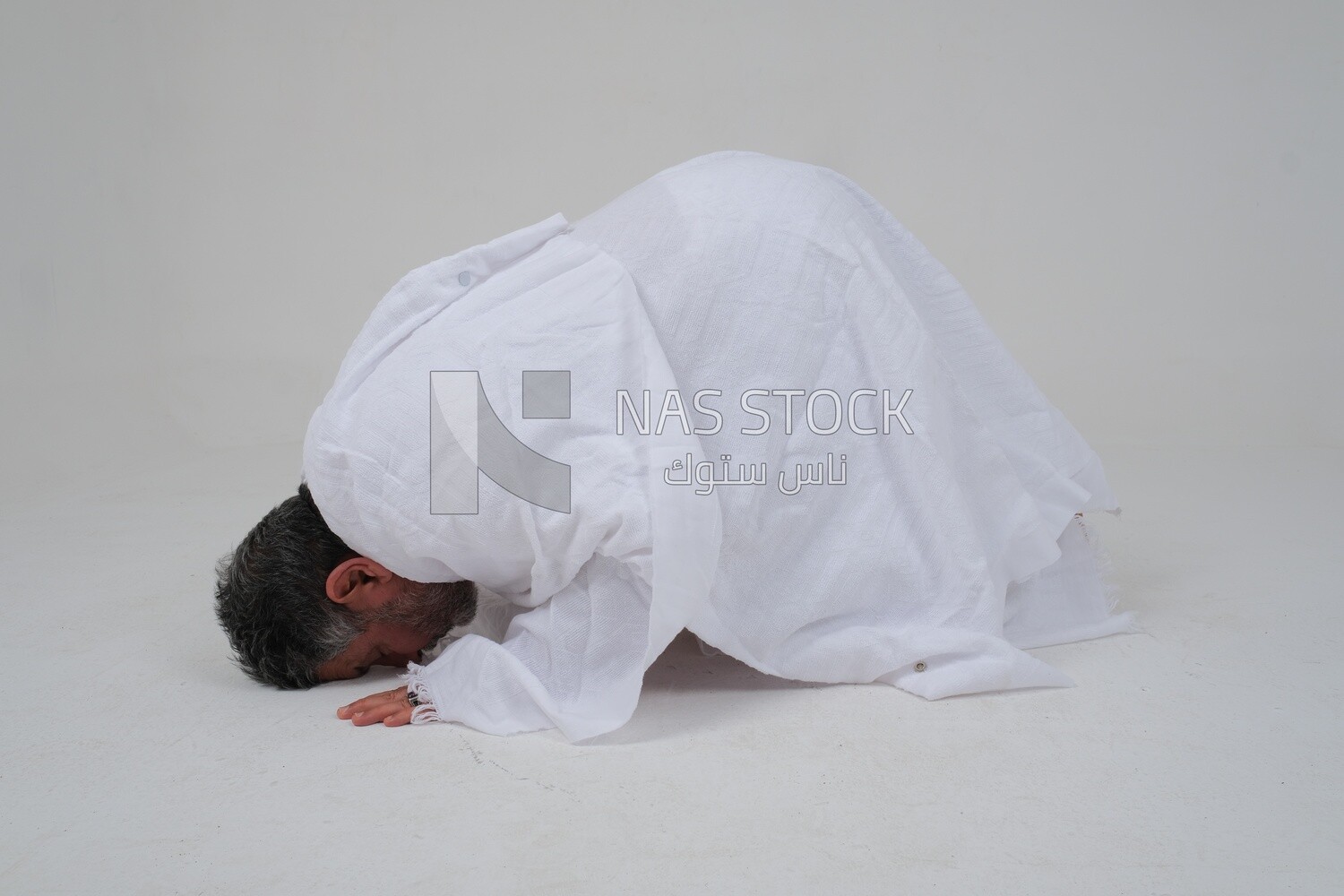 Saudi man wearing the Ihram dress, praying on the prayer rug, praying to god, Islam and worship, performing Hajj and Umrah, remembrances and supplications, white background, Saudi model