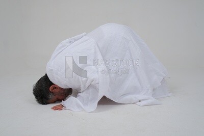 Saudi man wearing the Ihram dress, praying on the prayer rug, praying to god, Islam and worship, performing Hajj and Umrah, remembrances and supplications, white background, Saudi model