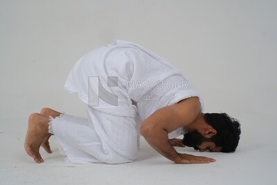 Saudi man wearing the Ihram dress, praying on the prayer rug, praying to god, Islam and worship, performing Hajj and Umrah, remembrances and supplications, white background, Saudi model