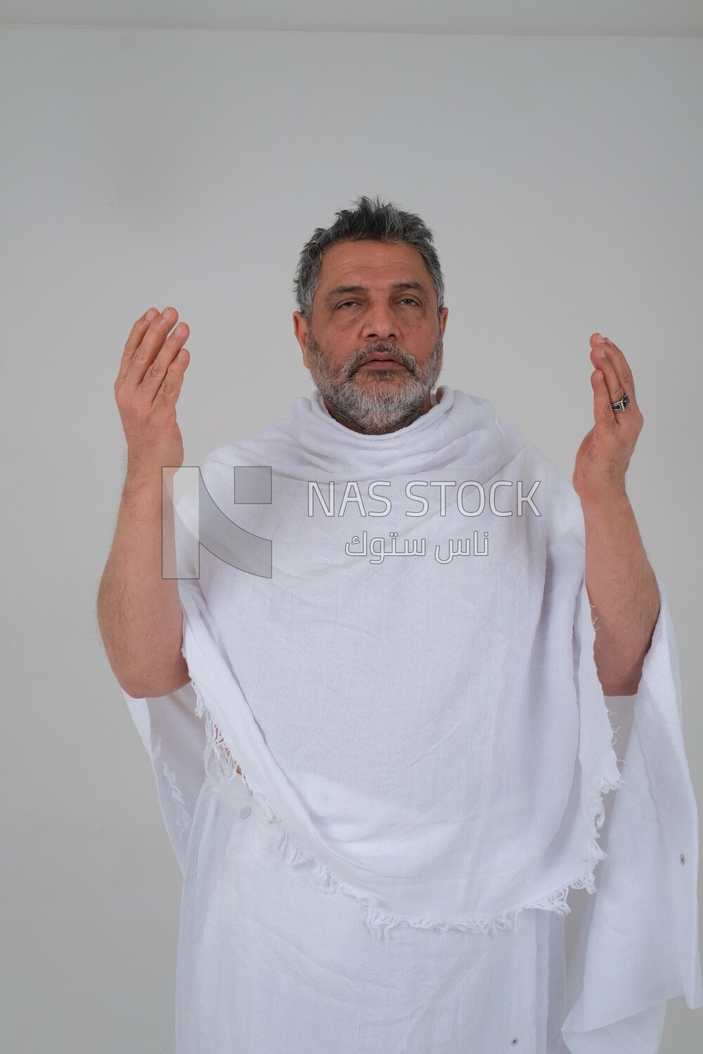 Saudi man wearing the Ihram dress and raising his hands to supplicate to God, Islam and worship, performing Hajj and Umrah, remembrances and supplications, white background, Saudi model