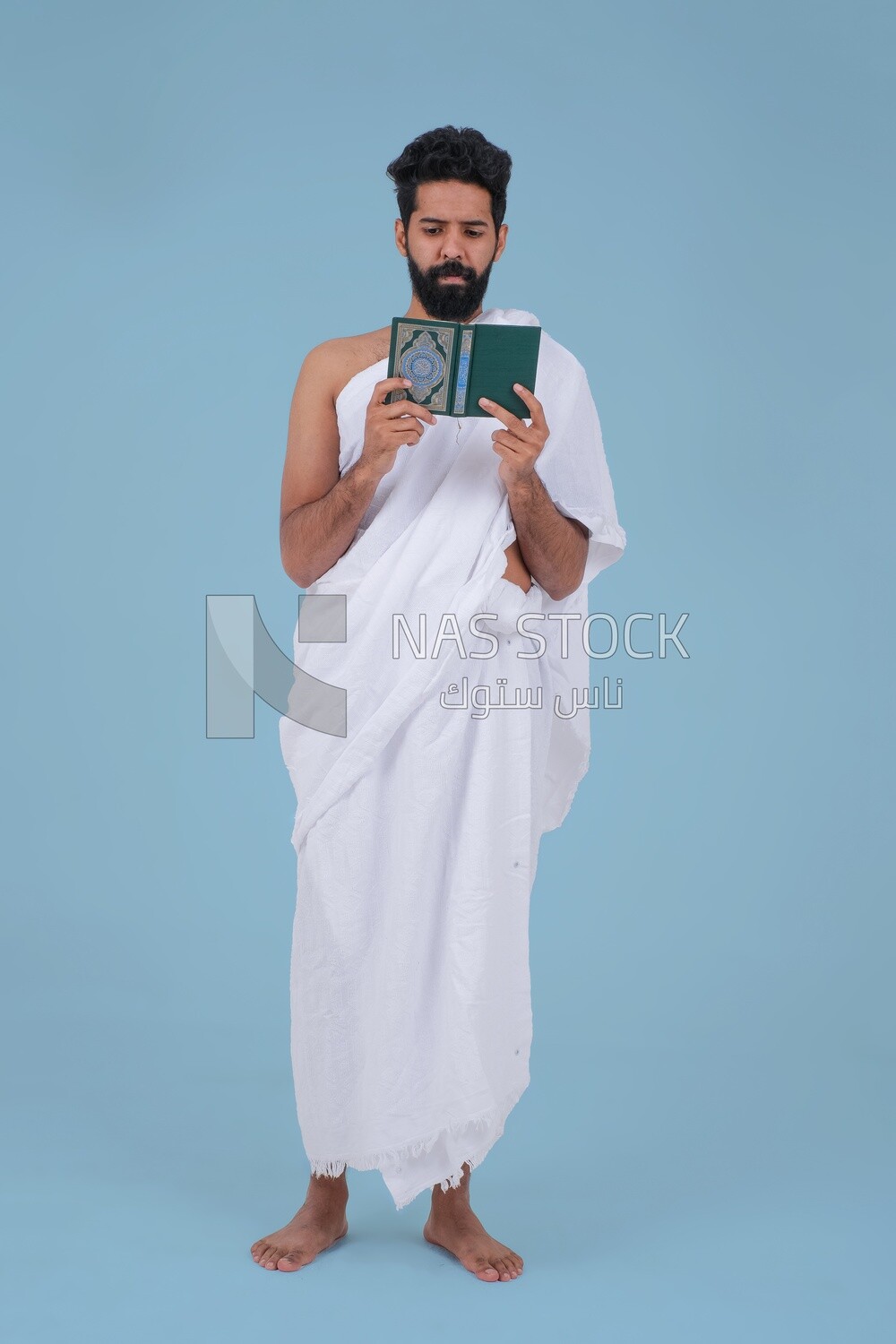 Saudi man wearing the Ihram dress and holding the Holy Quran book
