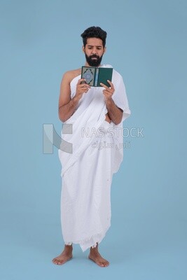 Saudi man wearing the Ihram dress and holding the Holy Quran book