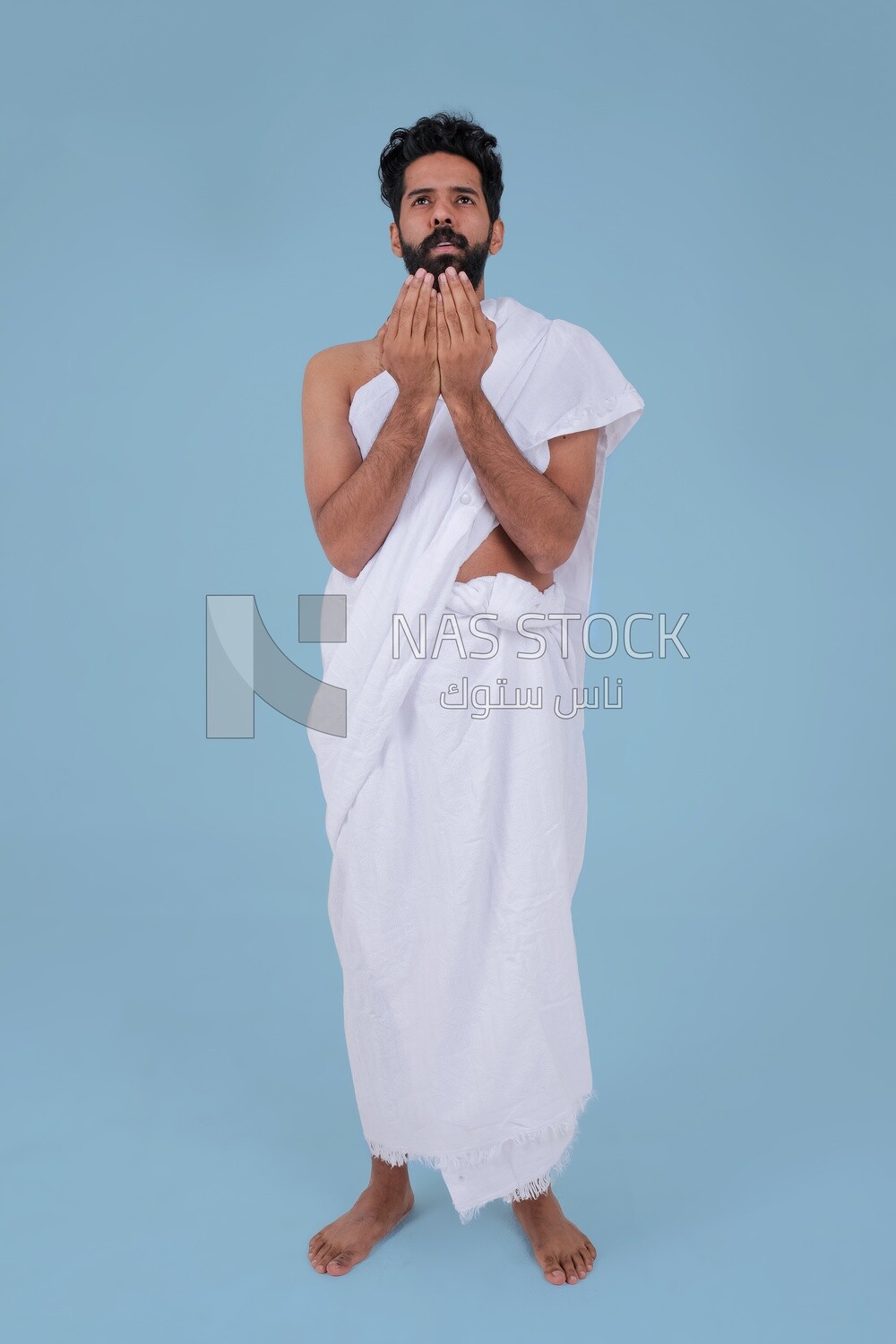 Saudi man wearing the Ihram dress and raising his hands to supplicate to God, Islam and worship, performing Hajj and Umrah, remembrances and supplications, Saudi model