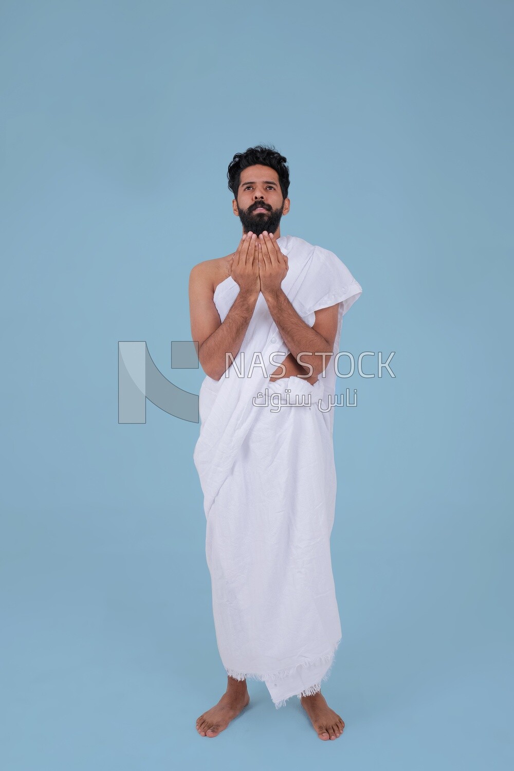 Saudi man wearing the Ihram dress and raising his hands to supplicate to God, Islam and worship, performing Hajj and Umrah, remembrances and supplications, Saudi model