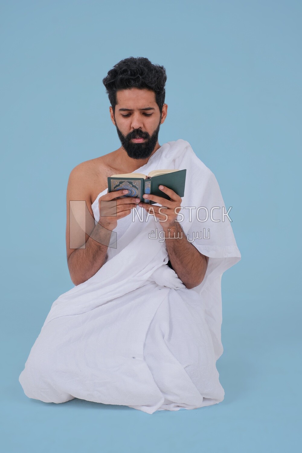Saudi man wearing the Ihram dress and holding the Holy Quran book, praying to god, Islam and worship, performing Hajj and Umrah, remembrances and supplications, Saudi model