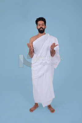 Saudi man wearing the Ihram dress and raising his hands to supplicate to God, Islam and worship, performing Hajj and Umrah, remembrances and supplications, Saudi model