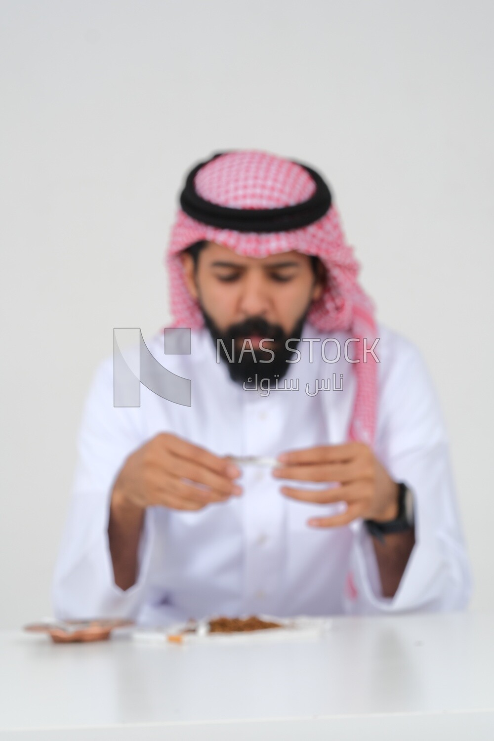 Saudi man wrapping cigarettes with his hands, tobacco addiction, cigarette addiction, harmful and toxic substance abuse, harmful behavioral habits, no smoking, Saudi model