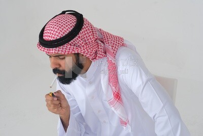 Saudi man wearing a white thobe and shemagh takes a deep breath from a cigarette, tobacco addiction, cigarette addiction, harmful and toxic substance abuse, harmful behavioral habits, no smoking, Saud
