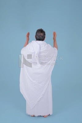 Back of a Saudi man wearing the Ihram dress and raising his hands to supplicate to God, Islam and worship, performing Hajj and Umrah, remembrances and supplications, Saudi model