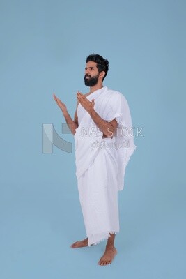 Side of a Saudi man wearing the Ihram dress and raising his hands to supplicate to God, Islam and worship, performing Hajj and Umrah, remembrances and supplications, Saudi model