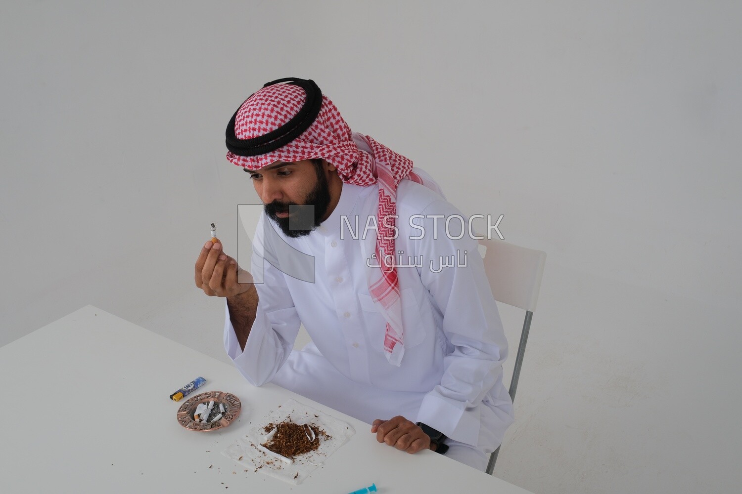 Saudi man wearing a white thobe and shemagh takes a deep breath from a cigarette, tobacco addiction, cigarette addiction, harmful and toxic substance abuse, harmful behavioral habits, no smoking, Saud