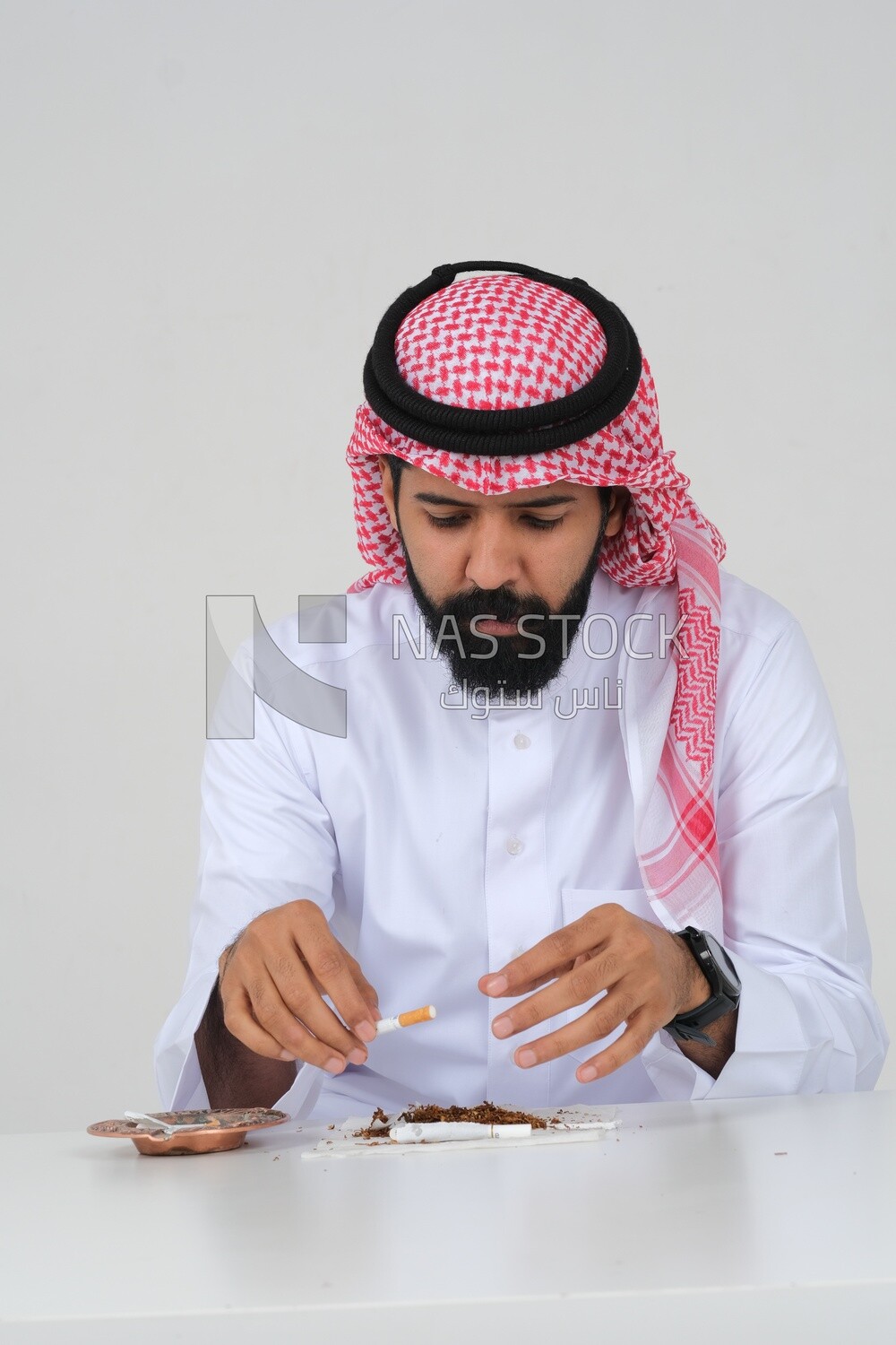 Saudi man wrapping cigarettes with his hands, tobacco addiction, cigarette addiction, harmful and toxic substance abuse, harmful behavioral habits, no smoking, Saudi model